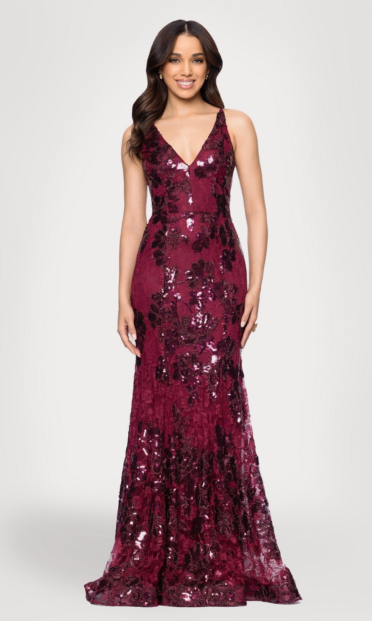 A woman faces forward wearing the Blondie Nites 5883BN, a fitted, floor-length prom dress in burgundy sequin lace with floral patterns.
